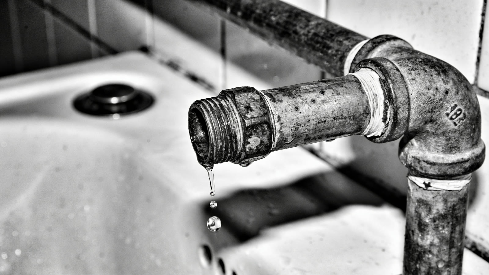 Tuyau de plomberie sous un évier avec une fuite d'eau et une bassine